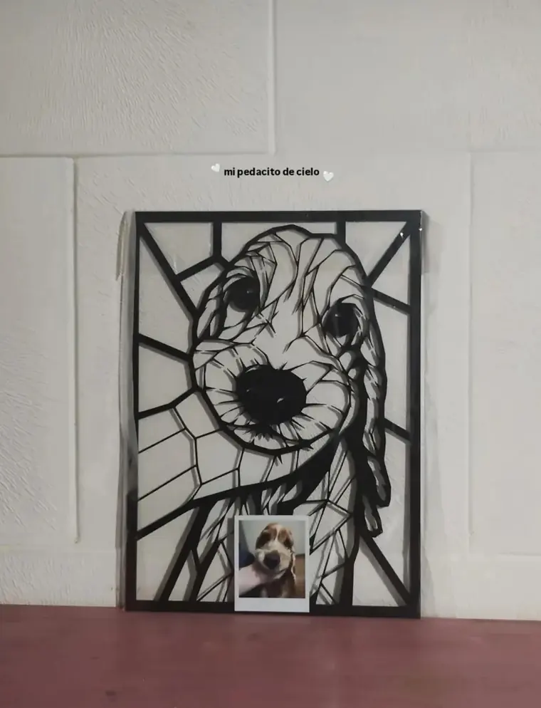 Retrato de un cachorro en corte láser apoyado en la pared, junto a la foto que lo originó
